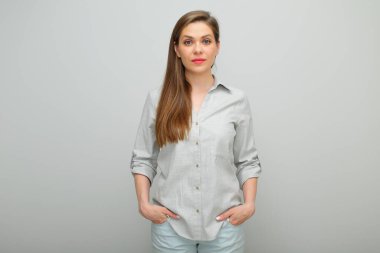 Ceplerinde elleri olan ciddi bir kadın, izole edilmiş bir kadın portresi, pantolon giymiş genç bir bayan ve gri bir gömlek..