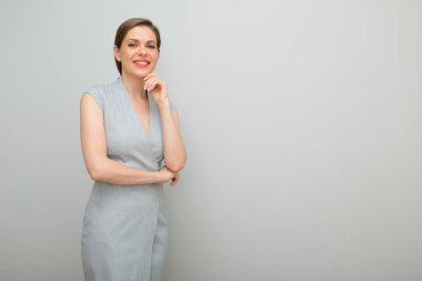 Kısa saçlı, çenesine dokunan, stüdyo resmi olan, gri elbiseli genç iş kadını..
