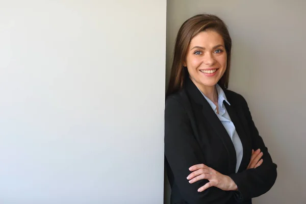 Smiling woman in business suit portrait with crossed arms.