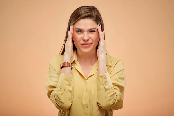 Young lady with headache touching head, isolated portrat on studio yellow background.