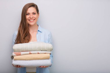 Elinde çamaşır yığını ya da çarşaf tutan gülümseyen bir kadının ön görüntüsü..