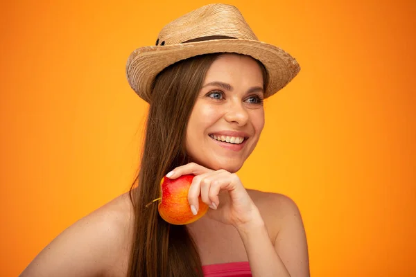 头戴草帽笑着的女人 手拿着红苹果 望着远方 脸庞女孩的画像被橙色的黄色背景隔开 — 图库照片