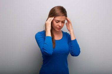 Baş ağrısı çeken yalnız bir kadın. Elleri başının üstünde. Mavi gömlekli, gözleri kapalı bir kadın portresi. Başını eğ..