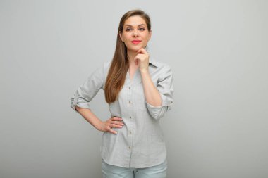 Ciddi bir kadının yüzüne dokunduğunu düşünmek, izole edilmiş bir kadın portresi, pantolon giymiş genç bir bayan ve gri bir gömlek..