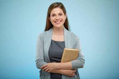 Kadın öğretmen ya da kadın yetişkin öğrenci açık mavi arkaplan üzerine kitapla izole edilmiş portre.