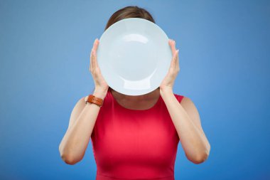 Kırmızı elbiseli kadın yüzünü beyaz plaka ile kaplamış, mavi arka planda izole edilmiş bir portre..