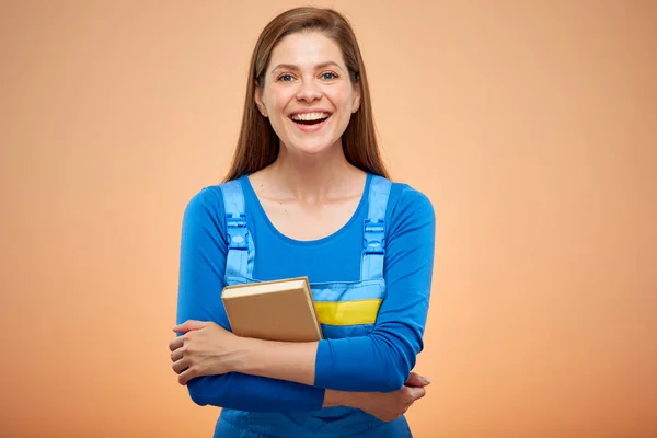 Smiling woman worker student in overalls with book. isolated female portrait on beige.