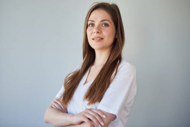 Uzun saçlı, beyaz gömlekli, kolları çapraz duran ve yüzünü çeviren gülümseyen bir kadın. izole edilmiş resim.