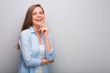 Yüzüne dokunan mavi gömlekli, gülümseyen bir kadın portresi. Mutlu bir iş kadını mı yoksa öğrenci mi?.