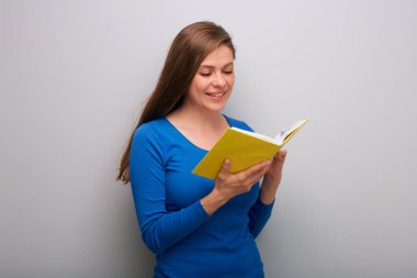 Kitap okuyan öğrenci kadın, gri duvarın yanında izole edilmiş portre..