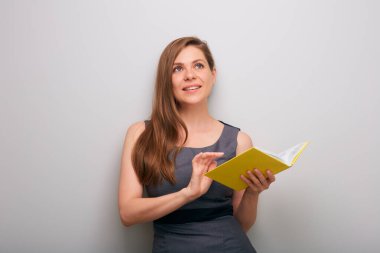 Açık sarı kitap gibi giyinmiş, gülümseyen ve yukarı bakan mutlu iş kadını. münzevi kadın iş adamı portresi.