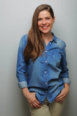 Gülümseyen, mavi kot gömlekli kadın, gri arka planda izole edilmiş bir portre. Dişleri olan geniş bir gülümseme.