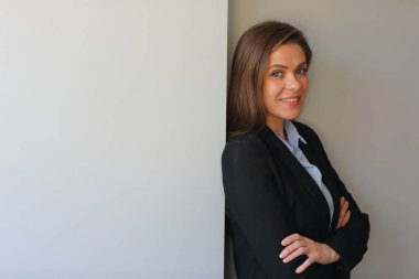 İş elbisesi giymiş, kollarını kavuşturmuş gülümseyen bir kadın..