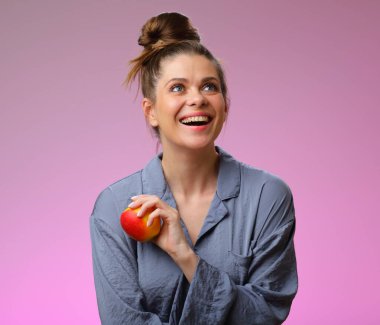 Gülümseyen kadın pijaması elmalı ve yukarı bakıyor, pembe kadın portresi üzerinde soyutlanmış.