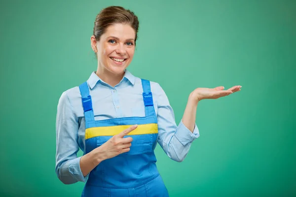 Smiling Woman Overalls Holding Empty Hand Pointing Finger Isolated Green — Stock Photo, Image
