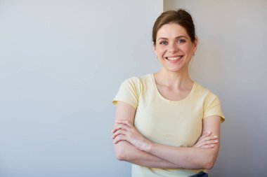 Sarı gömlekli, çapraz kollu, gülümseyen kadın..