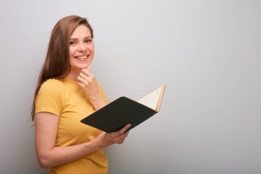 Açık kitabı olan öğrenci kadın gri duvarın yanında izole edilmiş portre..