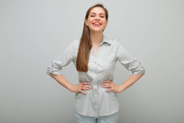 Gülümseyen, kendine güvenen, elleri kalçasında duran, izole edilmiş kadın portresi, pantolon giymiş ve gri gömlekli genç bayan..