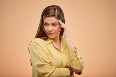 Başı ağrıyan genç bayan aşağıya bakıyor, stüdyo sarı arka planda izole edilmiş bir portre..