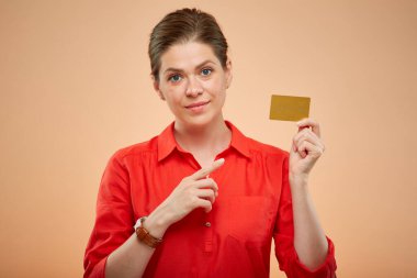 Kırmızı tişörtlü genç bayan elinde altın kredi kartı var ve parmağıyla işaret ediyor, izole edilmiş portre..
