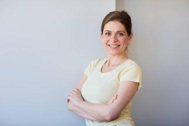 Sarı gömlekli, çapraz kollu, gülümseyen kadın..