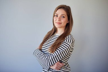 Çapraz kollu sıradan bir ayakta duran gülümseyen kadın. Mutlu bir kızın izole edilmiş portresi.