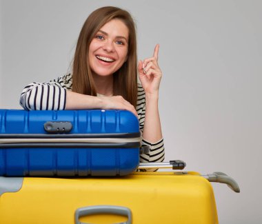 Gülümseyen kız bavula yaslandı ve parmağını kaldırdı. İki büyük seyahat çantalı bir kadın portresi..