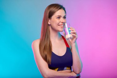 Spor giyim kuşamında gülümseyen, su içen ve başka tarafa bakan bir kadın. Neon çok renkli arkaplanda izole edilmiş kadın fitness portresi.