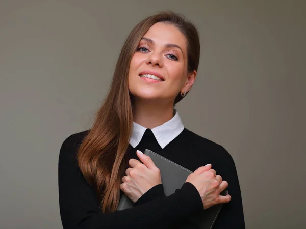 Smiling woman teacher in black suit with white collar holding book and arms crossed, isolated female portrait.