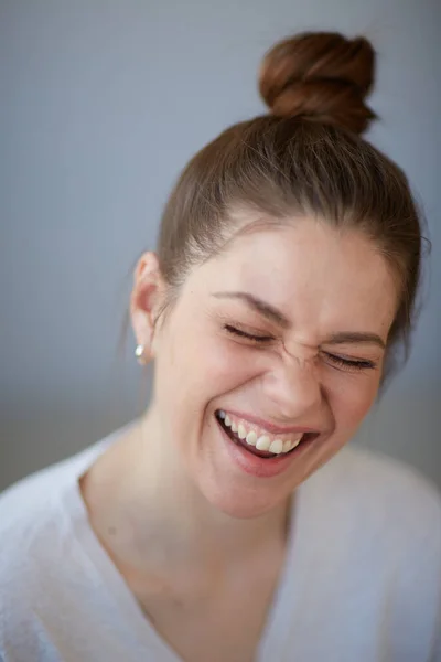 Laughing woman face portrait with closed eyes. Female head shot with shallow depth of field.