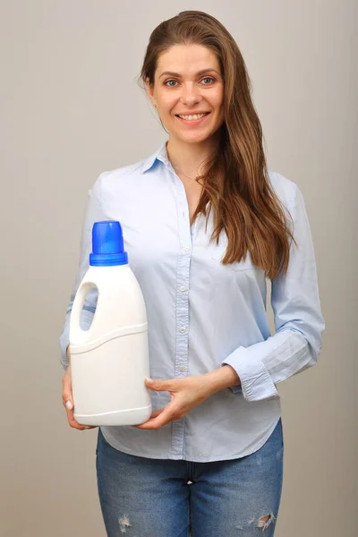 白いボトルの洗濯洗剤を前にした普段着を着た長髪の笑顔の女性 — ストック写真