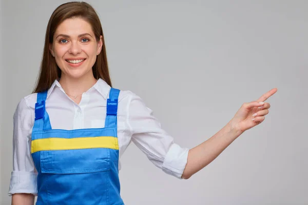 Glimlachende Vrouw Met Blauwe Overalls Wijst Naar Kopieerruimte — Stockfoto
