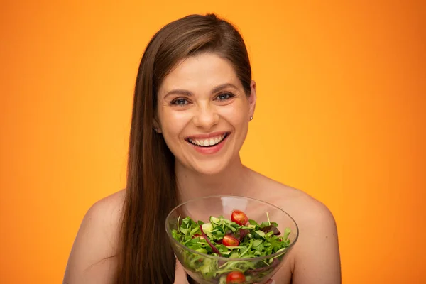 Happy laughing woman with bare shoulders holding green salad isolated portrait. Girl with long hair.
