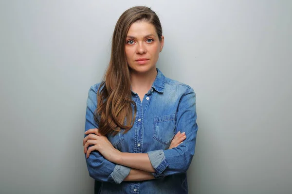 Serious woman in blue casual denim shirt with arms crossed. isolated female portrait.