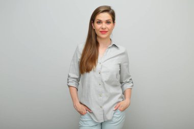 Elleri ceplerinde gülümseyen kadın, izole edilmiş kadın portresi, pantolon giymiş genç bayan ve gri gömlek..