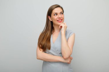 Gülümseyen kadın yüzüne dokunuyor ve başka tarafa bakıyor, gri iş elbisesi izole edilmiş portre..