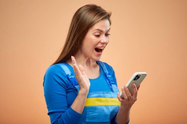 Tulumlu, akıllı telefon kullanan şaşırtıcı bir kadın. İzole kadın işçi portresi.