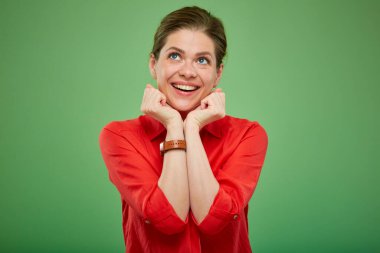 Kırmızı gömlekli, yeşil elbiseli bir kadın yukarı bakıyor. Gülümseyen kadın portresi.