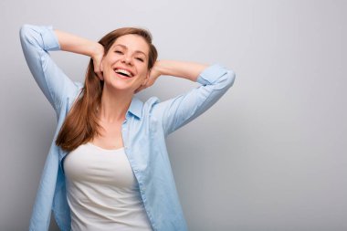 Elleri başının arkasında mutlu bir kadın. Gri duvar arka planında izole edilmiş kadın portresi.