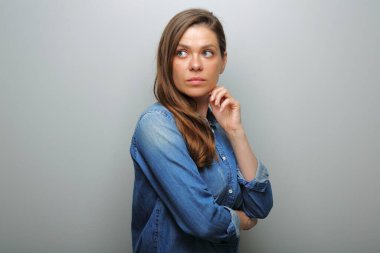 Mavi günlük kot gömlekli, omzunun üstünden bakan ciddi bir kadın. soyutlanmış kadın portresi.