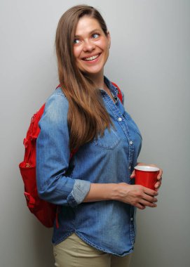 Gülümseyen kız öğrenci, omuzlarının üzerinden kahve bardağıyla izole edilmiş portreye bakıyor..