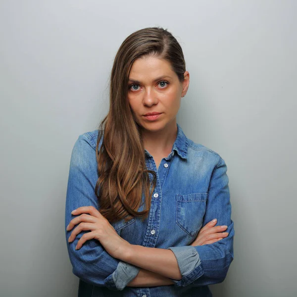 Serious woman in blue casual denim shirt with arms crossed. isolated female portrait.