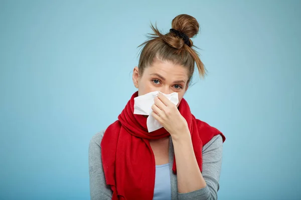 Sick woman with cold illness sneezing into tissue. Sick woman with cold flu isolated portrait on light blue.