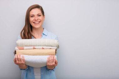 Elinde çamaşır yığını ya da çarşaf tutan gülümseyen bir kadının ön görüntüsü..