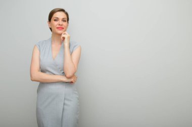 Kısa saçlı, çenesine dokunan, stüdyo resmi olan, gri elbiseli genç iş kadını..