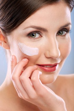 Yüzüne dokunan bir kadın, yüzüne krem sürmüş bir portre. Gülümseyen kız, güzel bir vesikalık..