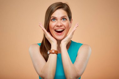 Yeşil gök mavisi elbiseli kadın portresi. Şaşırtıcı ve şaşırtıcı duyguları var. Şeftali rengi arka planda soyutlanmış.