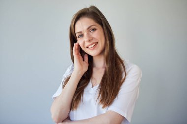 Yüzüne dokunan beyaz gömlekli, gülümseyen bir kadın. izole edilmiş resim.