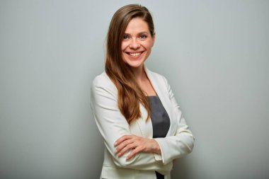 Beyaz takım elbiseli gülümseyen bir iş kadını kollarını kavuşturmuş, izole edilmiş bir portreyle duruyor..