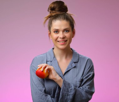 Elma tutan gülümseyen kadın pijaması, pembe kadın portresi üzerinde izole edilmiş.